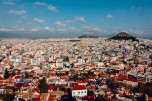 Aerial view of dense Athens apartment blocks with Lycabettus Hill under a blue sky