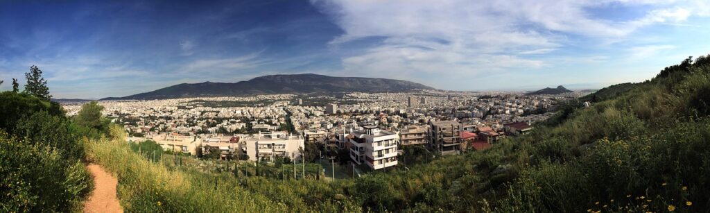 Panoramic view of Athens apartment blocks seen from a green, tree-covered hillside