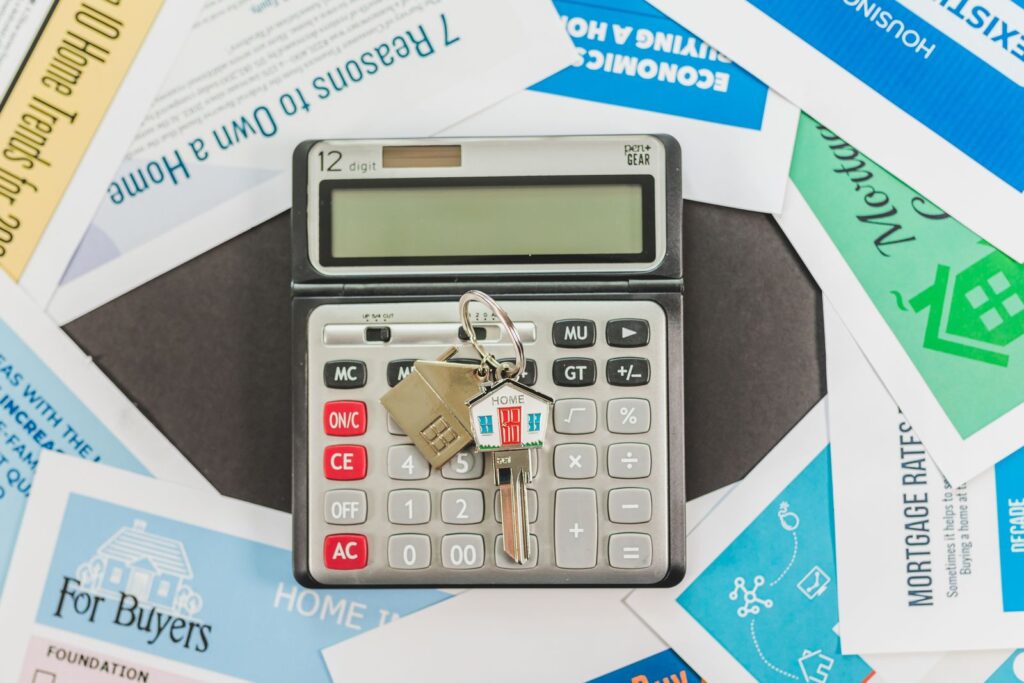 Calculator and a set of house keys resting on property purchase documents on a desk