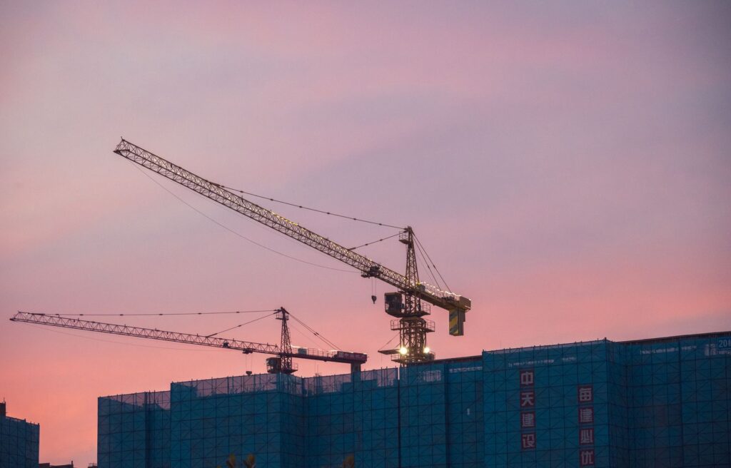 Construction crane rising above a block of flats at sunset