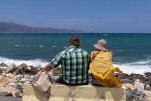 Couple sitting by the sea on the Heraklion waterfront in Crete on a sunny day