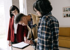 Young couple signing a property agreement at a table with a real estate agent