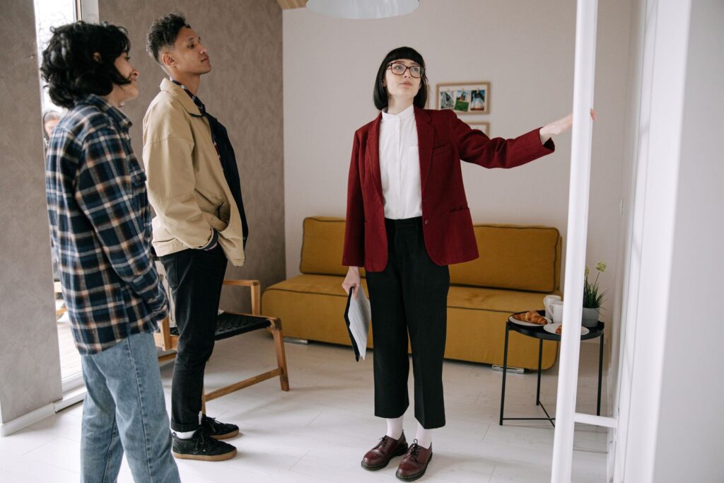 Estate agent guiding a couple through a furnished apartment during a viewing