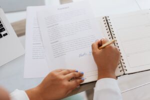 Close-up of hands signing a contract on a desk with office supplies