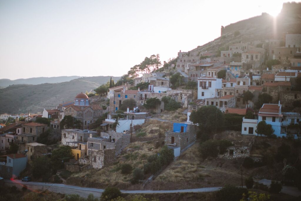 Traditional hillside village in Greece with stone houses and greenery at sunset