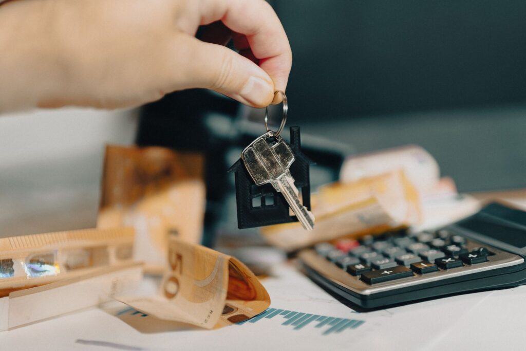 House keys resting on euro banknotes next to a calculator
