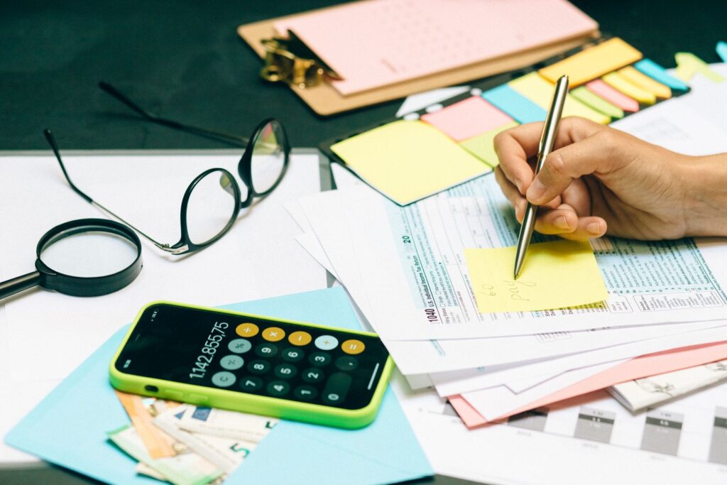 Office desk with paperwork, a calculator and glasses as a person writes notes