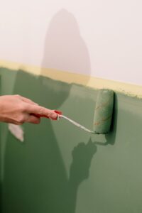 Person painting an interior wall with a roller during a home renovation