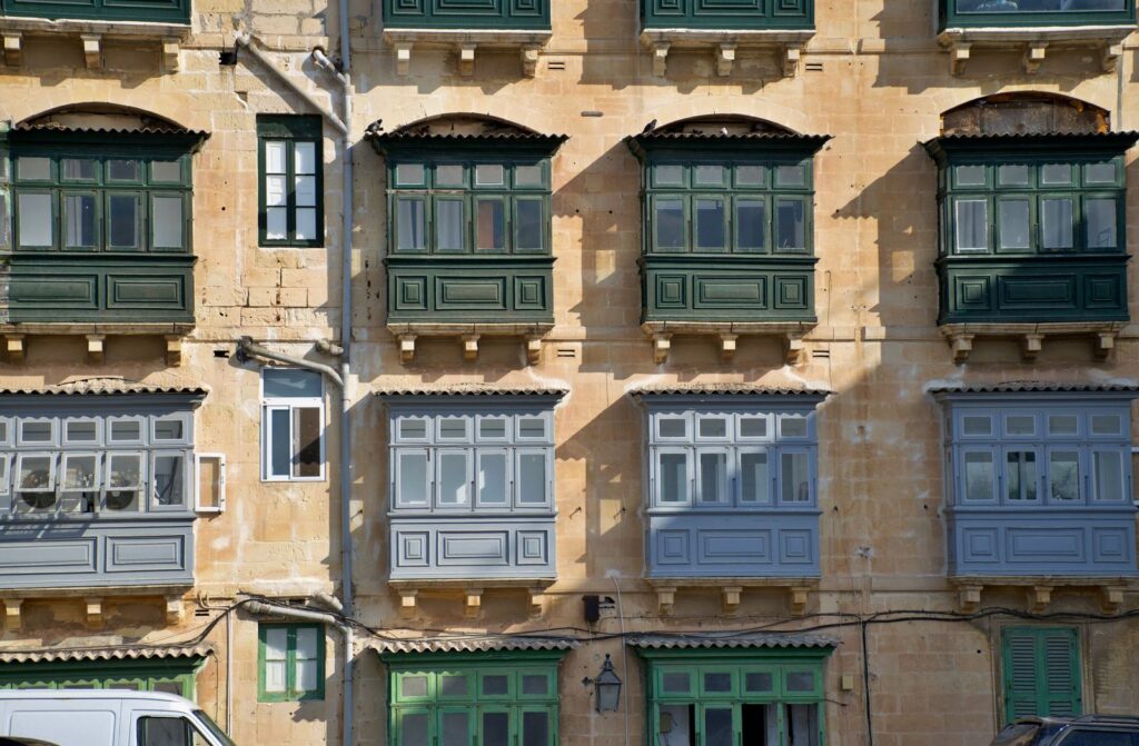 Traditional enclosed wooden balconies on limestone building facades in Malta
